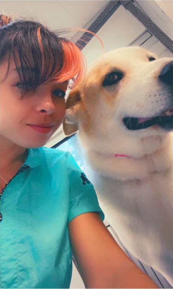 Dannielle Tyler standing beside a cream Labrador-type dog at a grooming appointment.